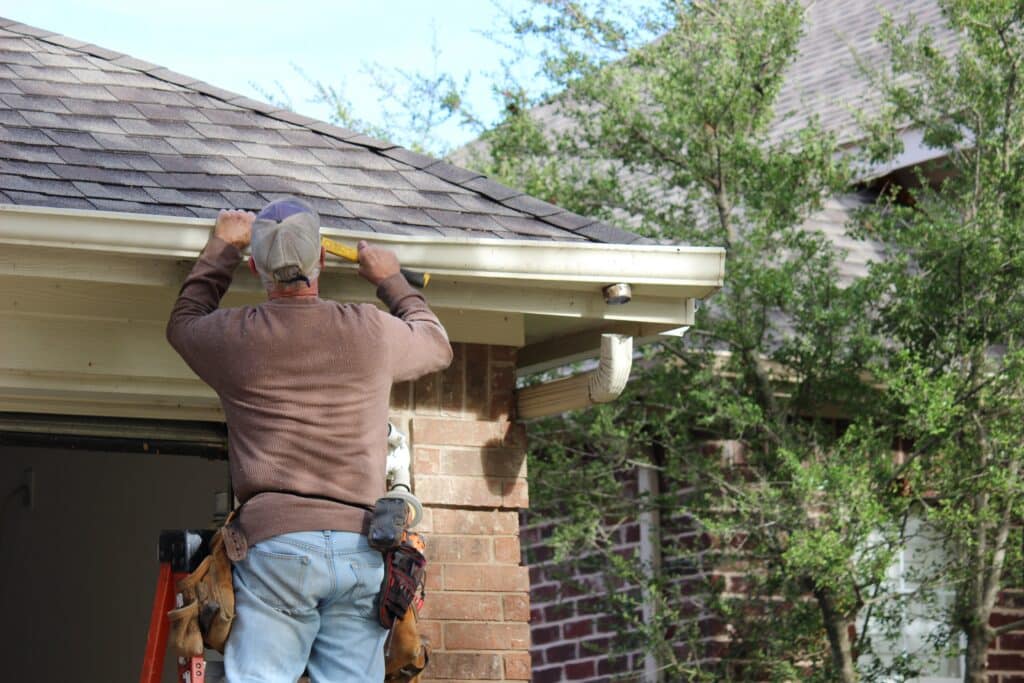 Contractor installing gutters on a residential building